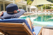 Woman lying and relaxing on deck chair by the pool. Summer holiday and vacation. 