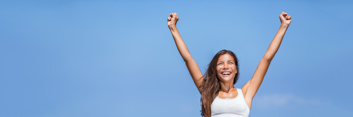 Wall Mural - Happy success woman winner. Asian girl cheering arms up of fitness challenge achievement on summer blue background. Panorama banner crop for copyspace on sky.