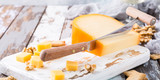 Fototapeta  - Delicious dutch gouda cheese with cheese blocks, crackers, walnuts and special knife on old wooden table.