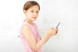 © amixstudio - Portrait of a little girl in front of a white wall holding a phone