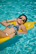 © ZoomTeam - Young pretty fashion woman body posing in summer in pool with clear water lying on mattress in blue bikini and having fun