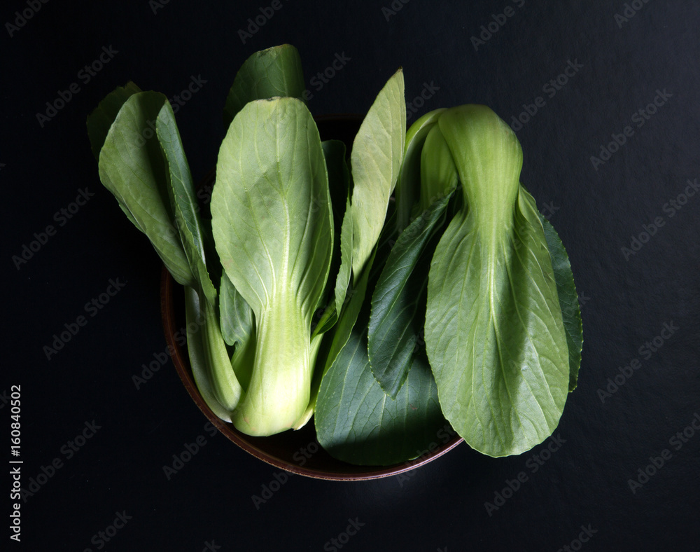 close up Fresh baby green bok choy in bowl on the  black background , overhead or top view shot - obrazy, fototapety, plakaty 