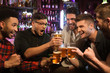 © Drobot Dean - Happy male friends clinking with beer mugs in pub