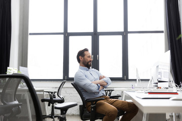 Wall Mural - Mature business man sitting on a chair with arms folded