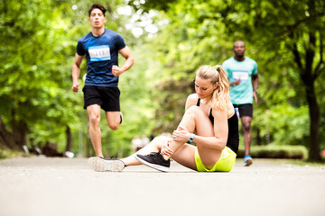 Wall Mural - Young woman at the competition with sprained ankle.