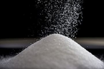 Close up shot of flowing sugar forming a pile as it falls