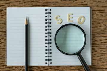 Aufkleber - search engine optimization concept with wooden alphabet abbreviation seo and magnification glass on 