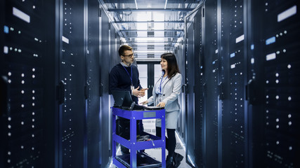 Wall Mural - Caucasian Male and Asian Female IT Technicians Working with Computer Crash Cart in Big Data Center full of Rack Servers.