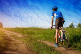 Fototapeta Lawenda - Young bicyclist riding in the field