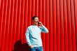 Smiling man talking on mobile phone on the background of red wall
