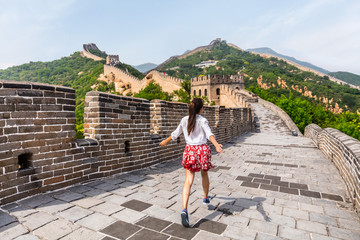 Happy cheerful joyful tourist woman at Great Wall of china having fun on travel smiling laughing and dancing during vacation trip in Asia. Girl visiting and sightseeing Chinese destination in Badaling