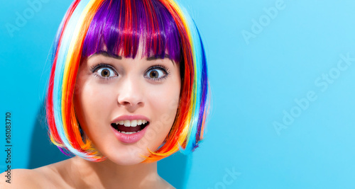 Beautiful woman in a colorful wig on a blue background