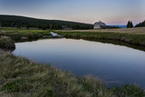 Fototapeta  - Small lake with clear water. Reflection of blue sky. Small house behind the lake during sunset. Czech nature.
