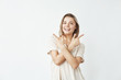 © Cookie Studio - Happy sincere young girl pointing fingers up smiling looking at camera over white background.