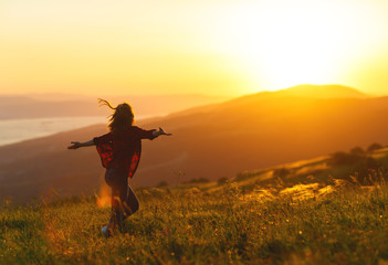 Happy woman  dances,  rejoices, laughs  on sunset in nature .