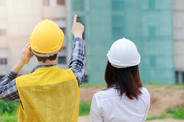 Foreman and women engineer checking work, commend worker by phone and point finger to the site workplace, Engineer checking work for control on site concept. copy space