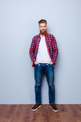 Wall Mural - Successful young stylish red bearded freelancer in bright casual shirt and jeans on pure background. So severe and serious