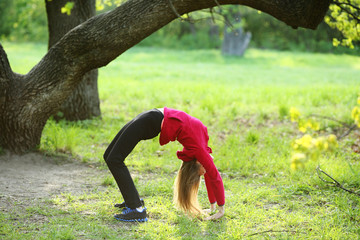 Stretching yoga young woman in green park, natural background