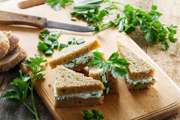 Simple cream cheese sandwiches with parsley and green onion on a table. Delicious healthy homemade snack. Close-up.