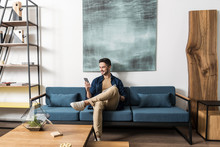 Happy Youthful Guy Bearded Resting With Cellphone In Living Room