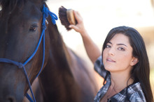 Young Woman Grooming Horse