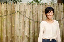 Mature Woman Standing By Garden Fence Smiling, Portrait