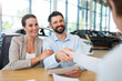 © pikselstock - Young couple with car dealer in auto salon