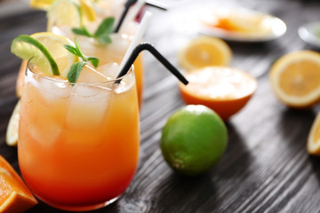 Wall Mural - Glass of Tequila Sunrise cocktail with fruits on wooden table