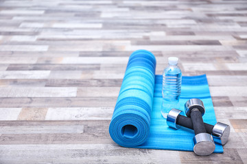 Wall Mural - Yoga mat with dumbbells and bottle of water on wooden floor