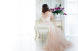 Beautiful girl bride in wedding gown sits at dressing table. Back view. Free space left