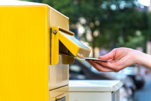 Throwing A Letter In A Yellow Mailbox