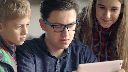 happy children talking and browsing internet on tablet by table at home