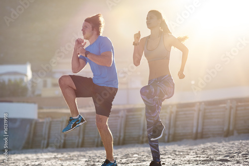 High knees. Couple Exercising On Beach