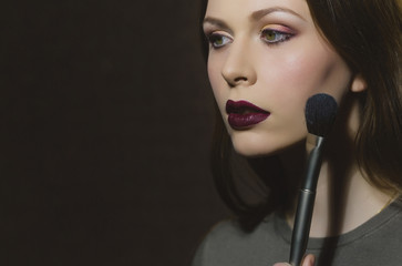 woman getting powder on face skin with makeup brush