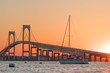 Sunset over Newport Bridge in Newport, Rhode Island.  There is a sailboat moored in front of the Newport Pell Bridge
