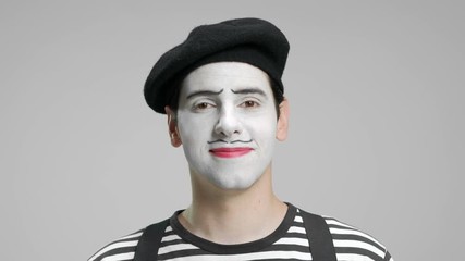 Canvas Print - Close-up of a mime looking at the camera and smiling isolated on gray background