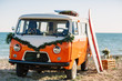 © boykovi1991 - bus with a surfboard on the roof is a parked near the beach