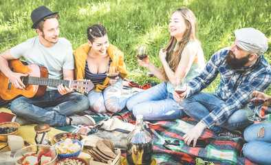 Friends group having fun outdoor cheering at bbq picnic with vintage guitar - Young people enjoying summer time together at barbecue garden party - Youth friendship concept - Focus bearded hipster guy