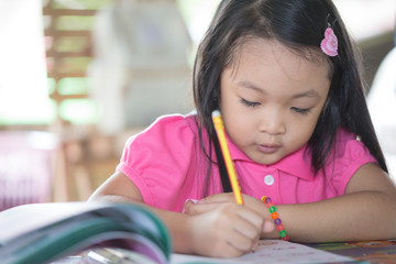 Little asian kid at home doing homework