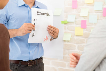 teacher showing example paper to students while doing group work in classroom