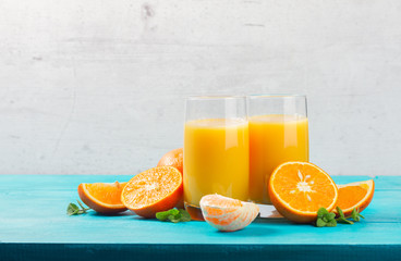 Orange juice - two glasses on wooden table, copy space on gray wall