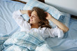 © Елена Кравчук - Smiling young woman in white shirt, lying in bed, good morning