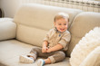 © cirkoglu - Nicely dressed and happy little boy with blue eyes sitting on the sofa.