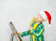 © Ermolaev Alexandr - Pensive boy in a red christmas hat holding roller for painting