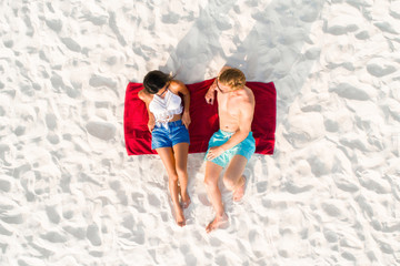 Top view of couple lying on the beach taking a sunbath in summer