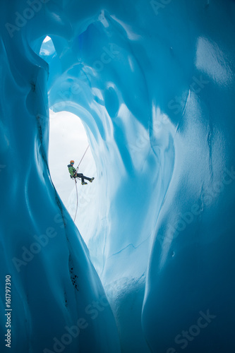 Fotografía Man Rappelling past opening of blue ice cave on Matanuska Glacier, Alaska