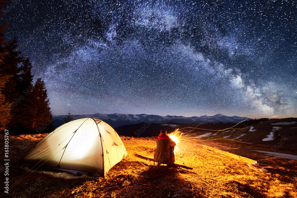 Male hiker enjoying in his camp near the forest at night. Man sitting ...