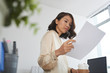 © DragonImages - Low angle portrait of young Asian businesswoman reading document at office