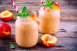 Peach smoothies in a mason jar with mint on wooden background