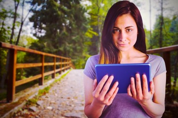 Poster - Composite image of portrait of brunette holding digital tablet 